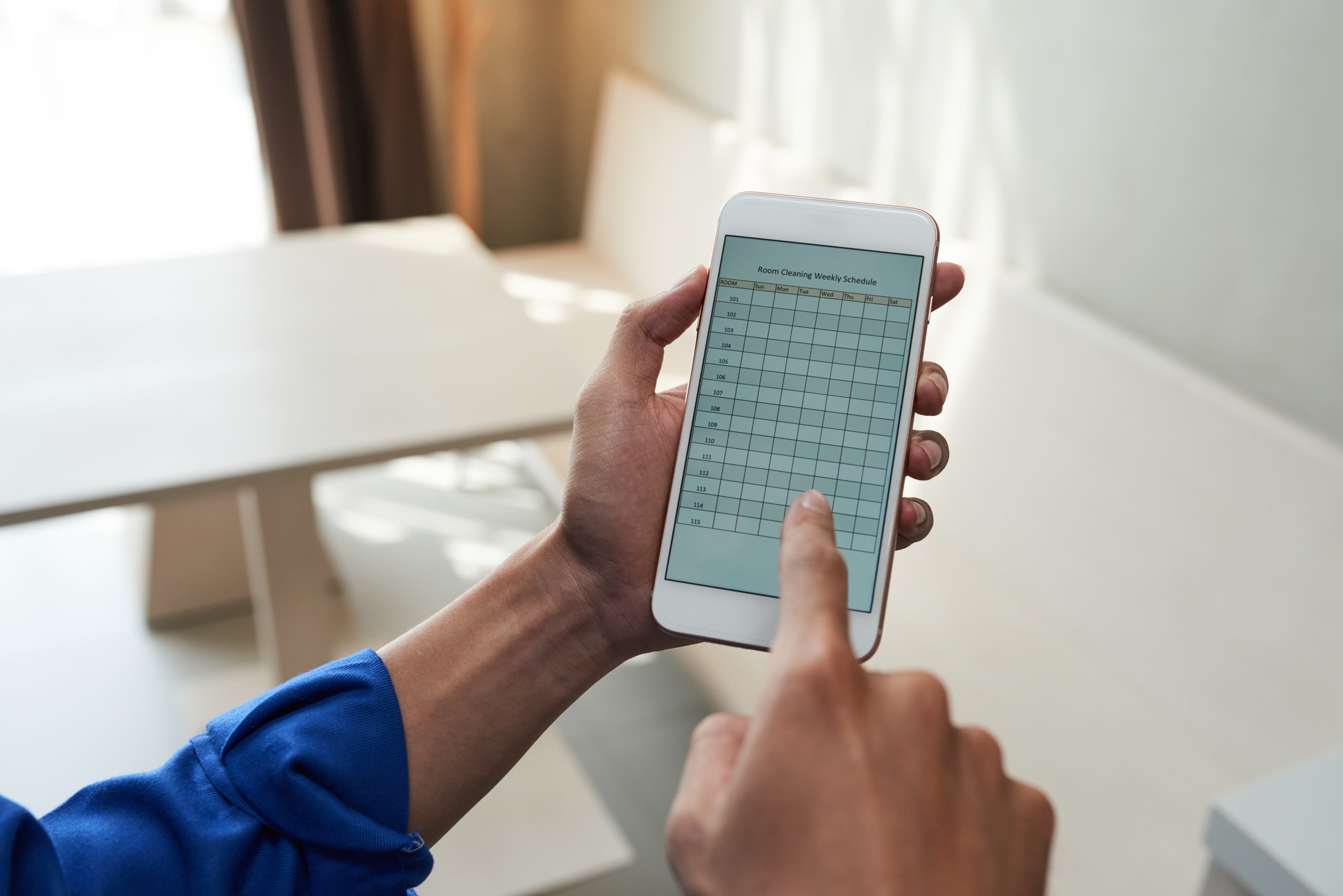 Hand holding a smartphone displaying a mobile punch list application.